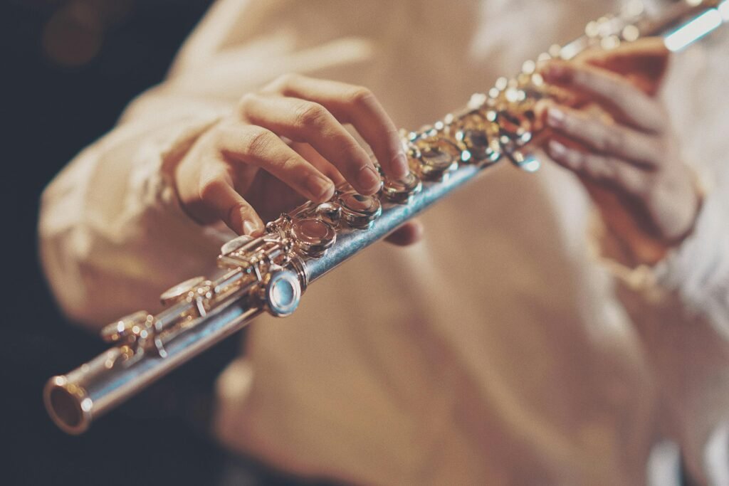 Focused image of a musician's hands playing a silver flute during a performance.
